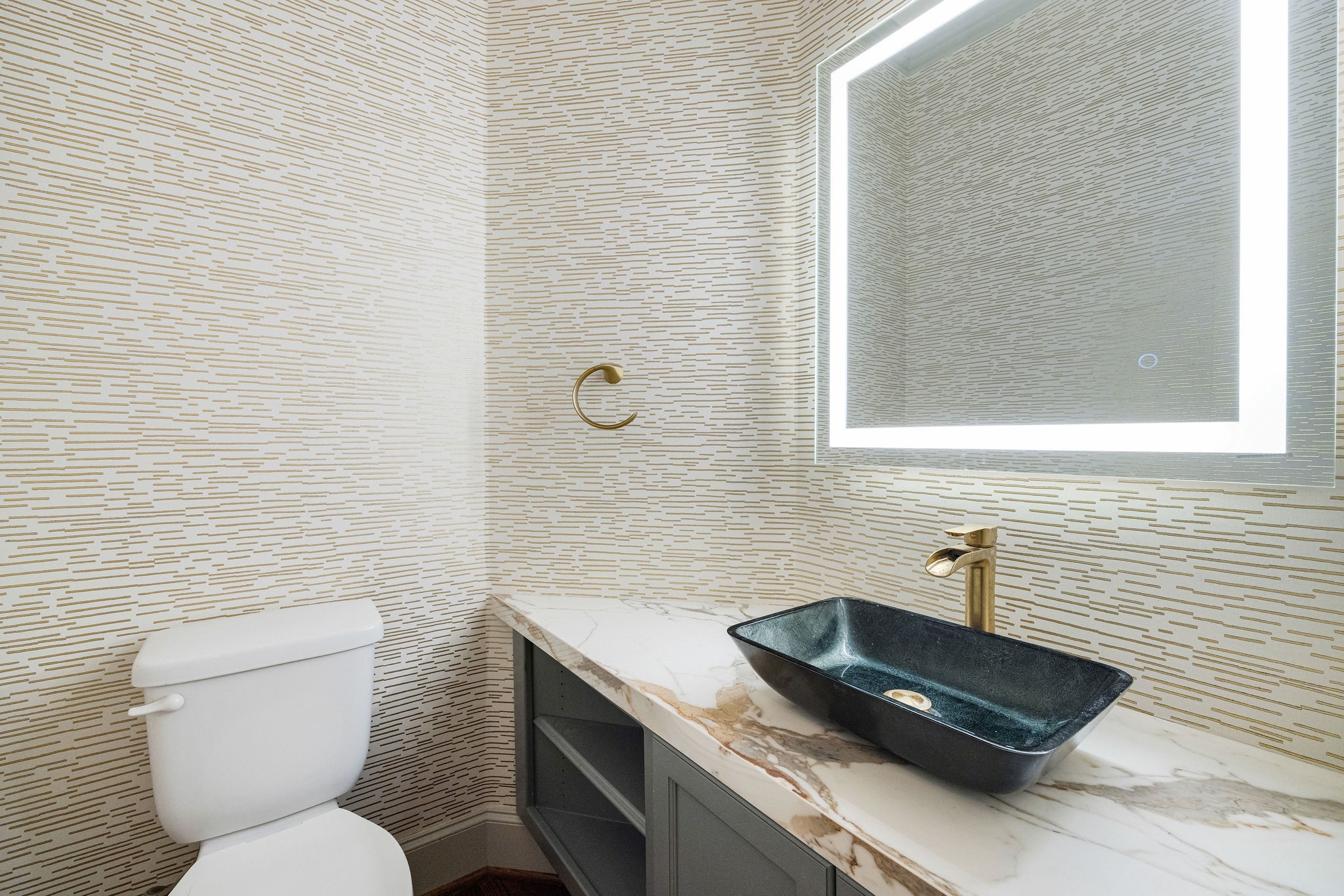2415 Commonwealth Street Houston, TX 77006 - Photo 15 of 26 Hidden just beyond the kitchen and wine bar, the elegant powder room makes a lasting impression with its statement vessel sink, illuminated mirror, and custom designer wall treatment.