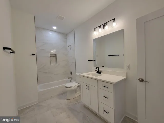 a bathroom with a toilet a sink a mirror a bathtub and shower