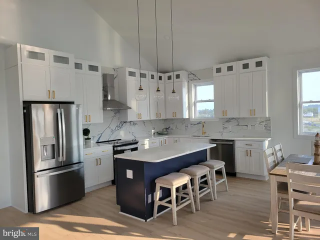 a kitchen with stainless steel appliances granite countertop a dining table chairs stove refrigerator and cabinets