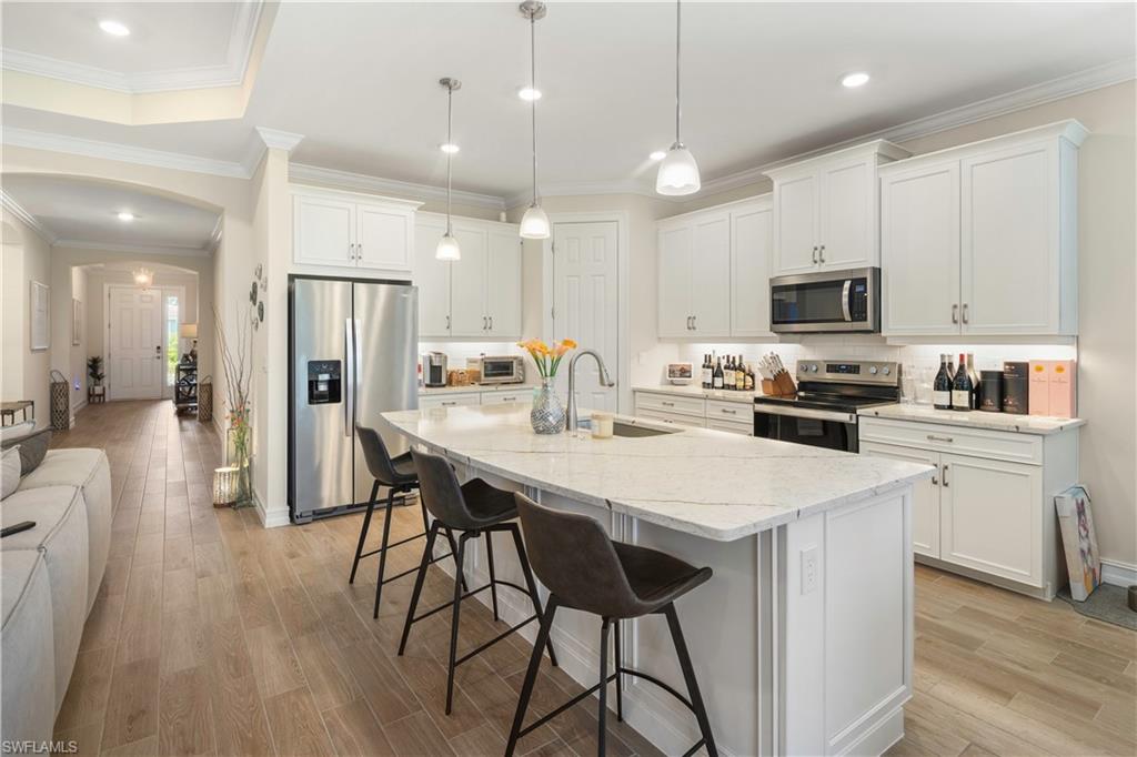 329 Deauville Loop Naples, FL 34114 - Photo 6 of 22 a kitchen with stainless steel appliances a table chairs refrigerator and microwave