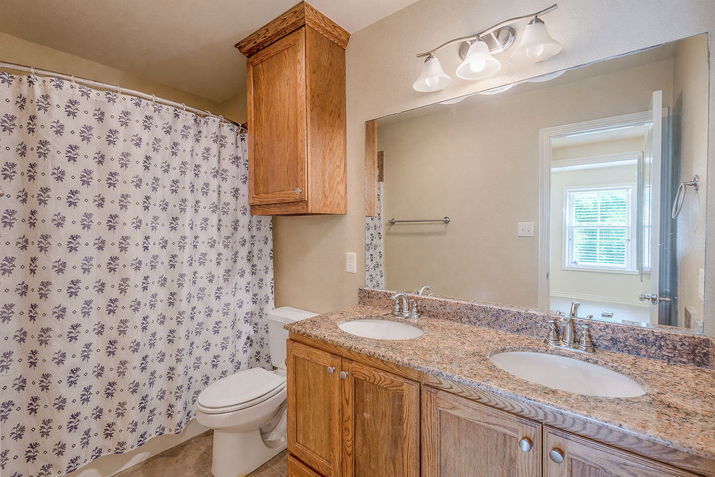 3309 Keefer Loop College Station, TX 77845 - Photo 19 of 27 a bathroom with a granite countertop sink a toilet and a mirror
