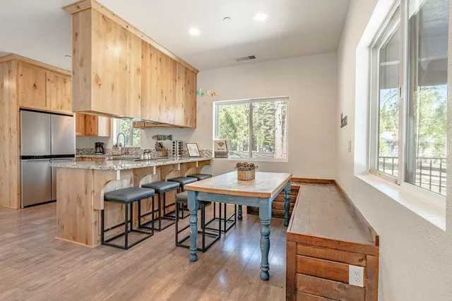 a kitchen with stainless steel appliances granite countertop a stove a refrigerator a kitchen island a table and chairs in it