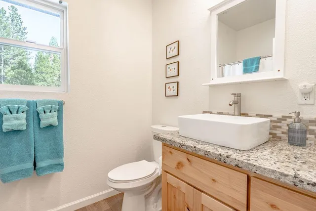 a bathroom with a granite countertop toilet sink and mirror