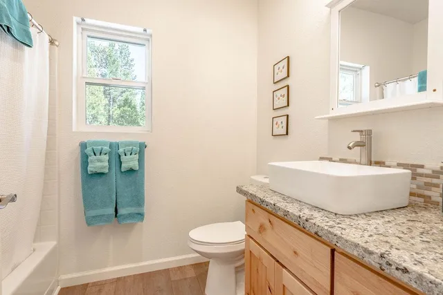 a bathroom with a granite countertop sink a toilet and mirror