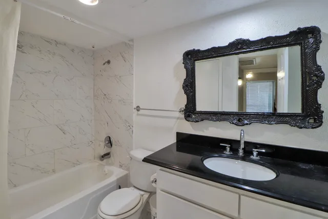 a bathroom with a granite countertop sink toilet a mirror and bathtub