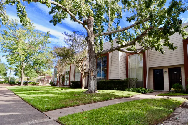 a tree in front of a house with a yard