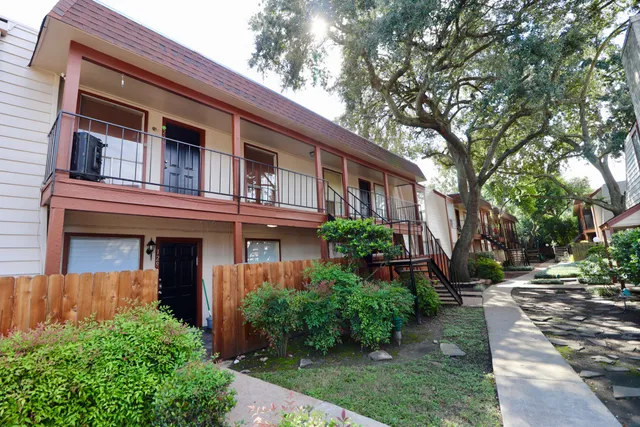 a front view of a house with a yard and potted plants