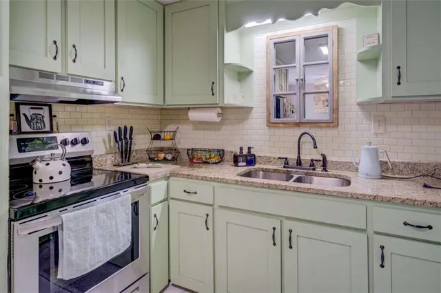 a kitchen with stainless steel appliances granite countertop white cabinets sink and stove