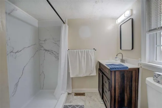 a bathroom with a granite countertop sink a toilet and shower