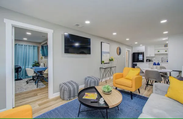 a living room with furniture kitchen view and a wooden floor