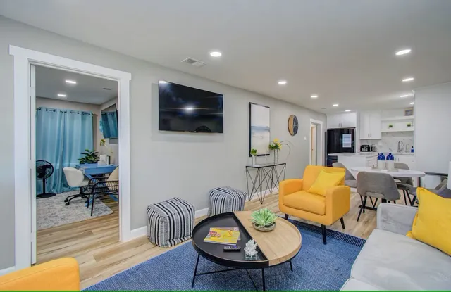 a living room with furniture kitchen view and a wooden floor