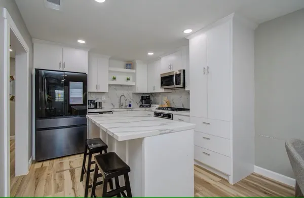 a kitchen with kitchen island white cabinets appliances and refrigerator