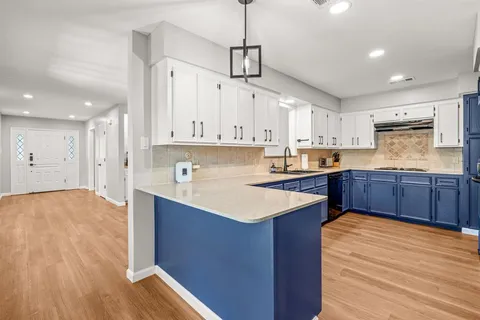 a kitchen with stainless steel appliances granite countertop a sink stove and white cabinets with wooden floor