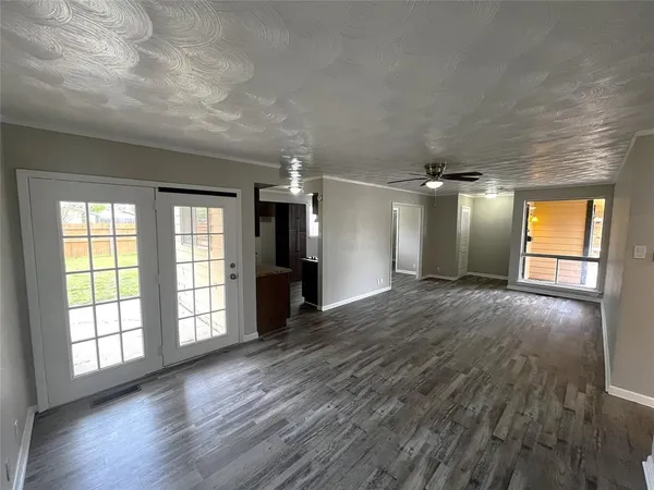 an empty room with wooden floor and windows