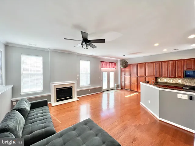 a living room with stainless steel appliances furniture a fireplace and a kitchen view