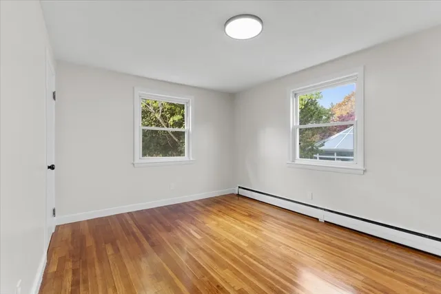 a view of empty room with window and wooden floor