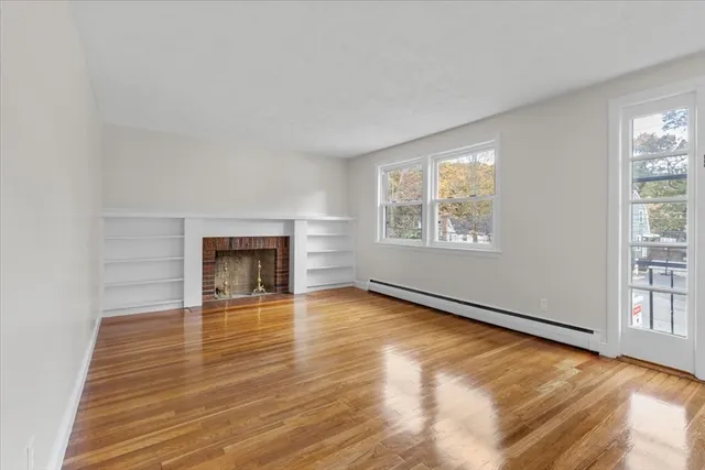 wooden floor fireplace and windows in an empty room