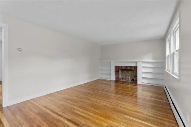 a view of empty room with wooden floor and fireplace