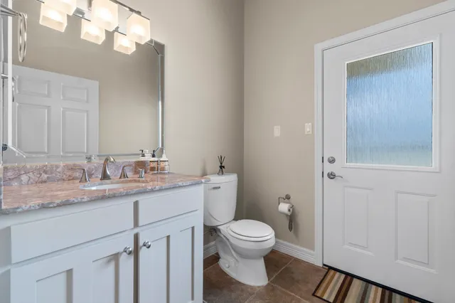 a bathroom with a granite countertop sink mirror and toilet