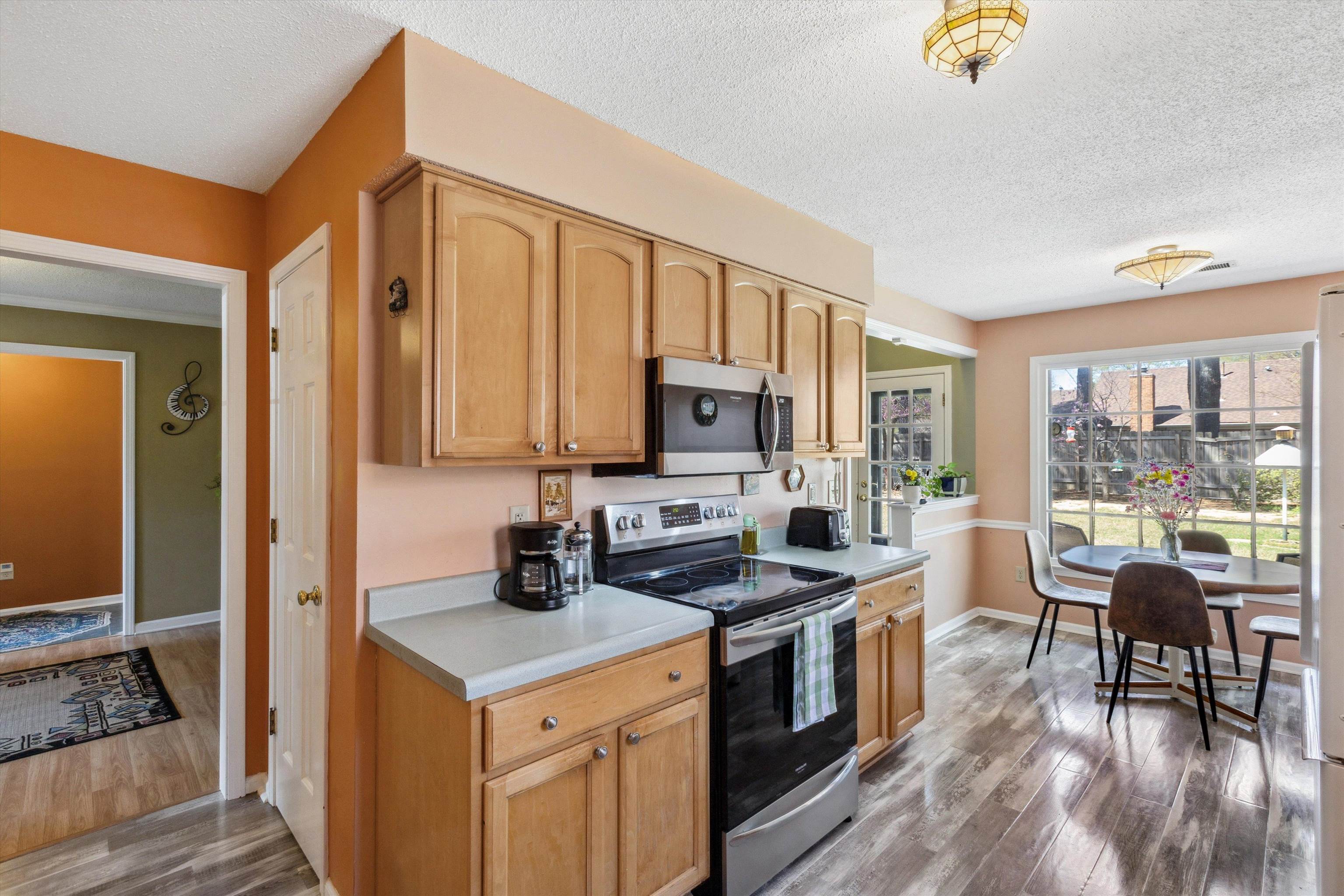 6972 Crestridge Road Memphis, TN 38119 - Photo 11 of 26 Kitchen featuring light countertops, stainless steel appliances, baseboards, a textured ceiling, and dark wood-style floors