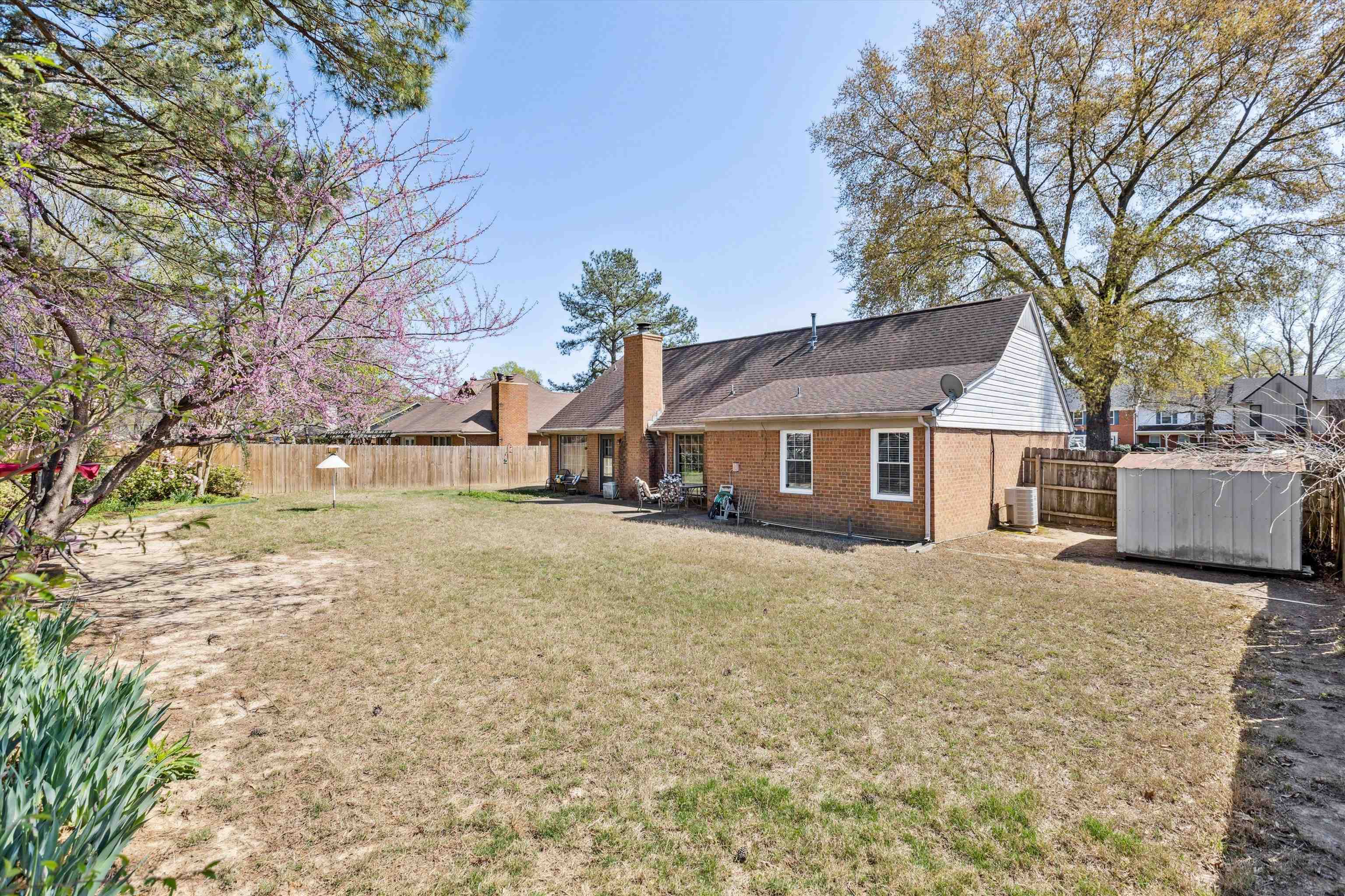 6972 Crestridge Road Memphis, TN 38119 - Photo 25 of 26 Back of house with central air condition unit, a chimney, a fenced backyard, brick siding, and a yard