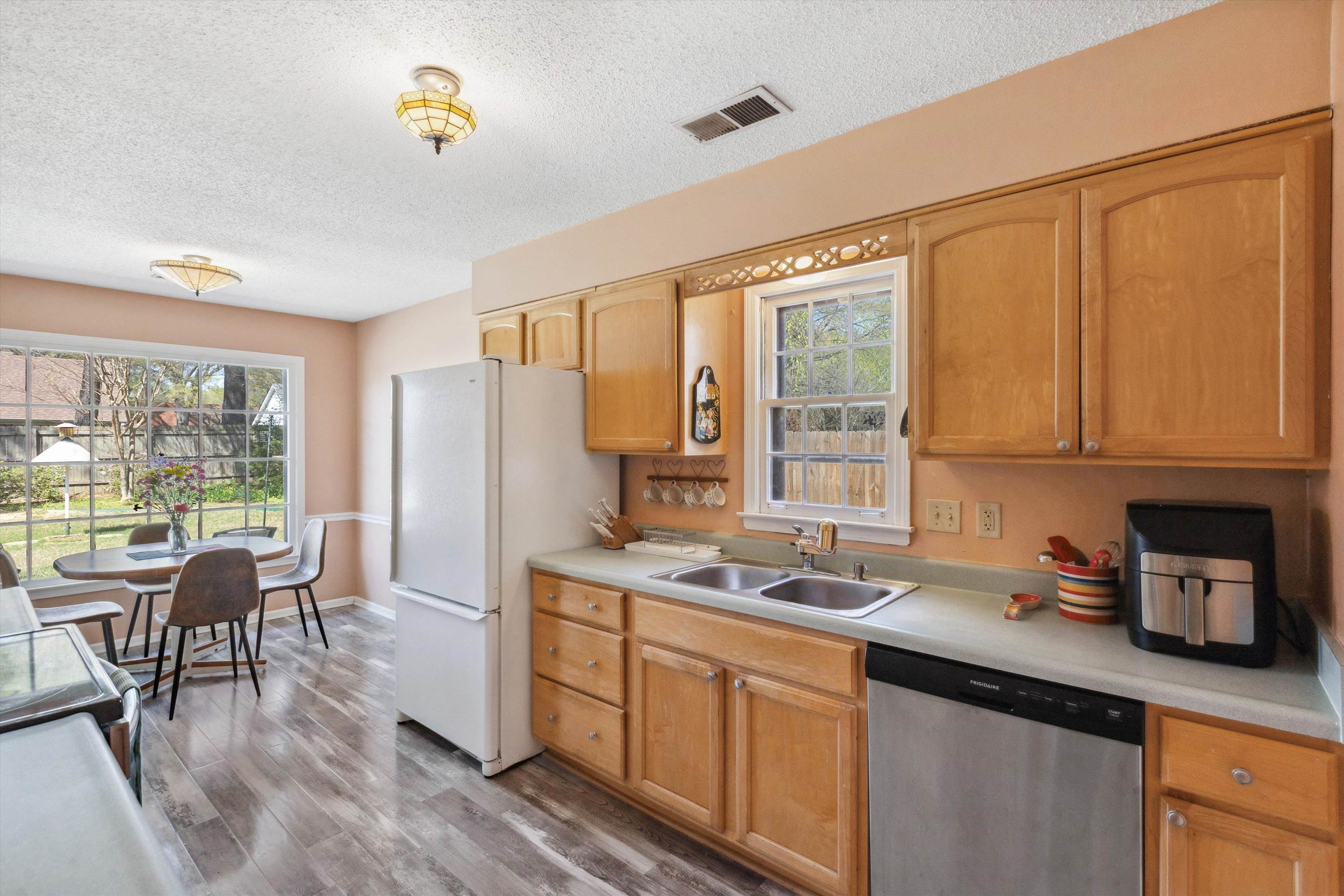 6972 Crestridge Road Memphis, TN 38119 - Photo 10 of 26 Kitchen featuring light countertops, visible vents, a sink, light wood-style floors, and stainless steel dishwasher