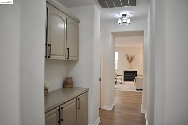 a view of a hallway with wooden floor and cabinet