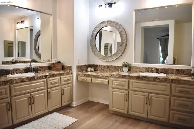 a bathroom with a granite countertop double vanity and a mirror