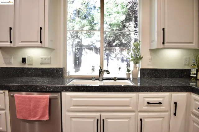 a kitchen with granite countertop white cabinets and white appliances