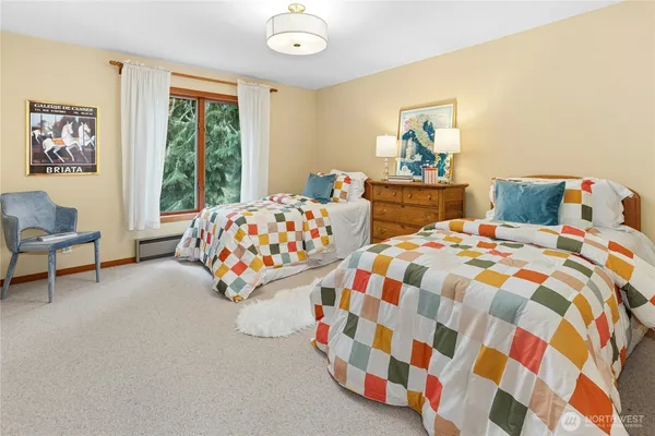 a bedroom with two beds and a lamp next to a window