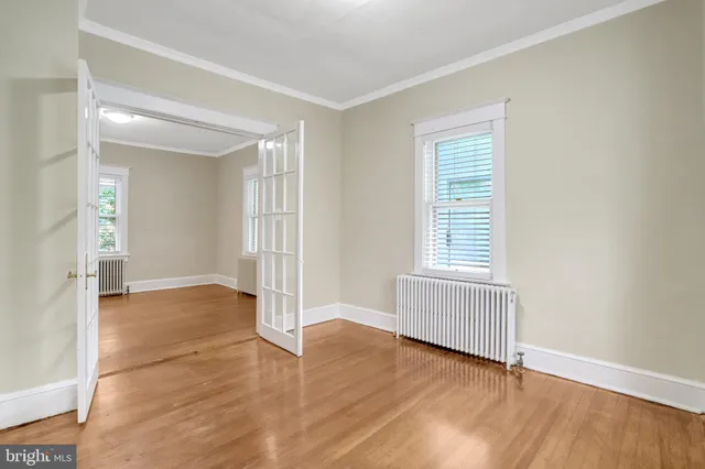 an empty room with wooden floor and windows