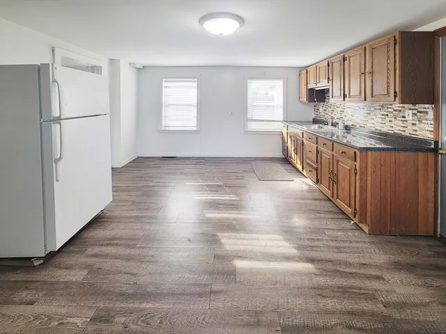 a view of kitchen and empty room with wooden floor