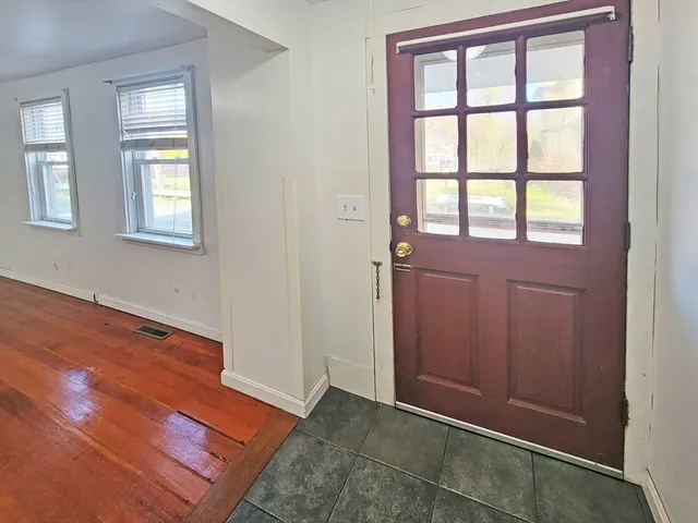 an empty room with wooden floor closet and windows