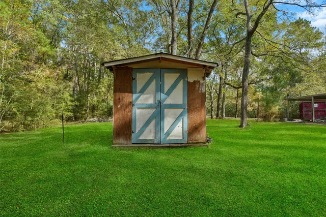 a view of backyard with a barn and large trees