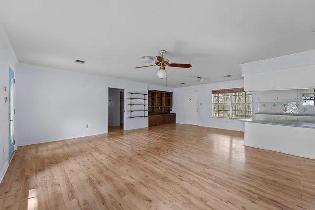 a view of an empty room with a window and wooden floor