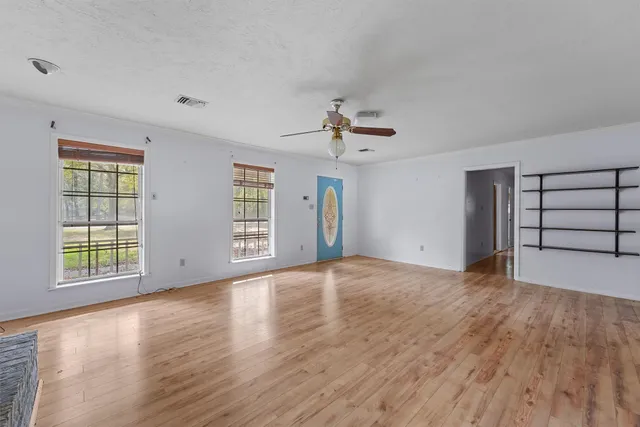 a view of an empty room with a window and wooden floor