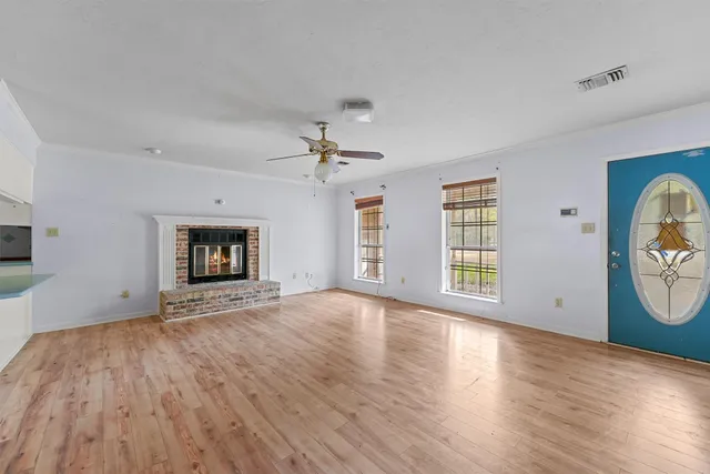 an empty room with wooden floor fireplace and windows