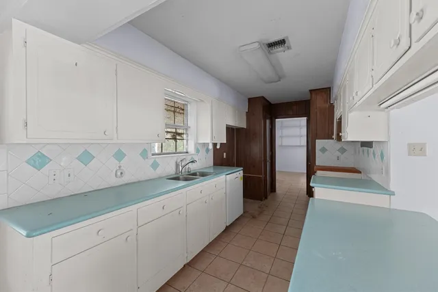 a large white kitchen with a sink and dishwasher a refrigerator with white cabinets