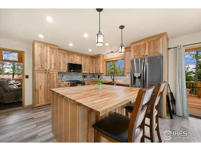 a open kitchen with stainless steel appliances granite countertop a refrigerator a stove a sink dishwasher and a dining table with wooden floor