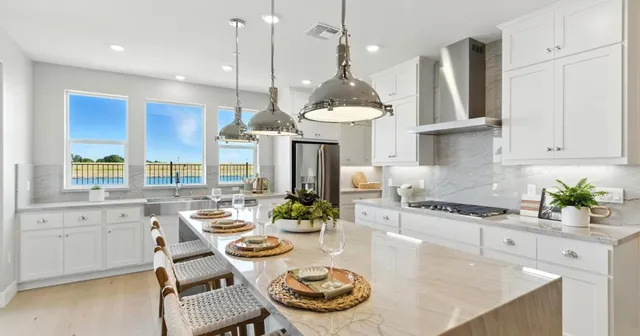 a dining hall with stainless steel appliances kitchen island granite countertop a table and chairs in it