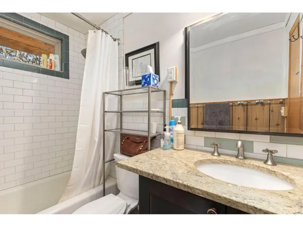 a bathroom with a granite countertop sink a mirror and shower