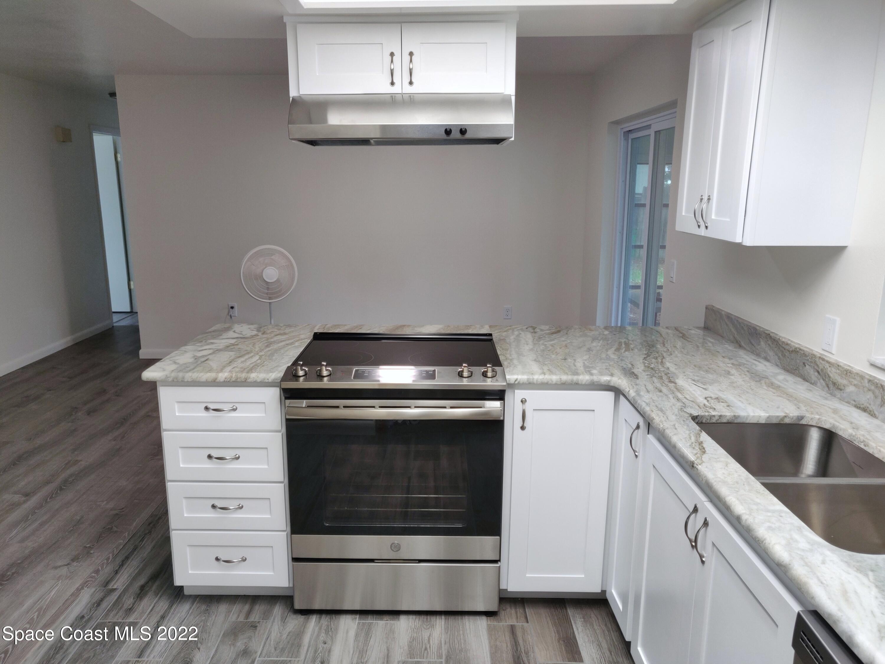 3649 Longbow Road Cocoa, FL 32926 - Photo 5 of 34 a kitchen with granite countertop white cabinets and white appliances