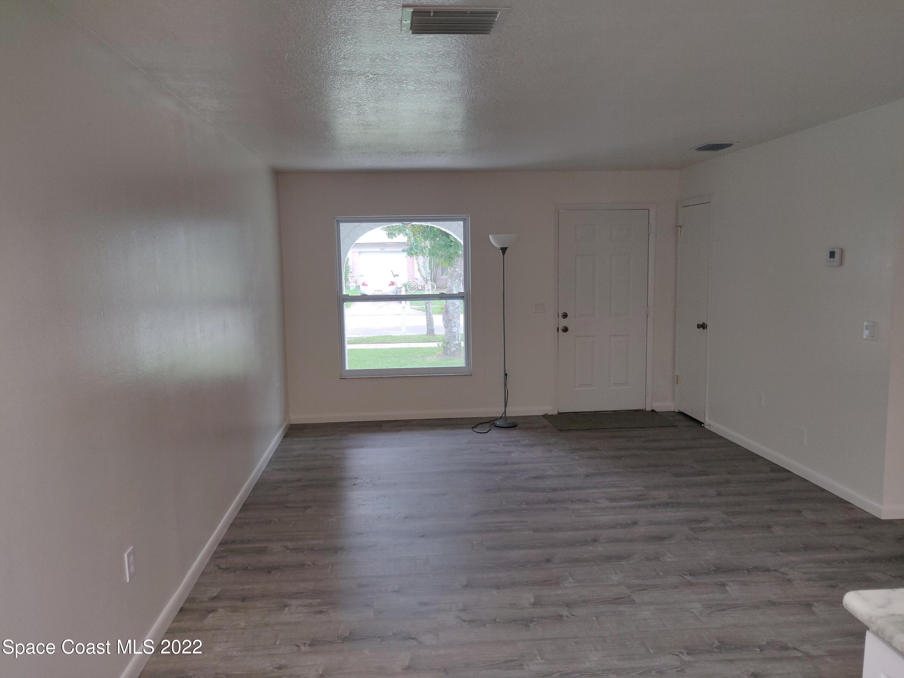 3649 Longbow Road Cocoa, FL 32926 - Photo 8 of 34 an empty room with wooden floor and windows