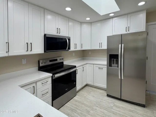 a kitchen with granite countertop white cabinets and white appliances