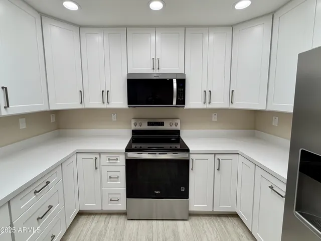 a large kitchen with a large counter top space appliances and cabinets