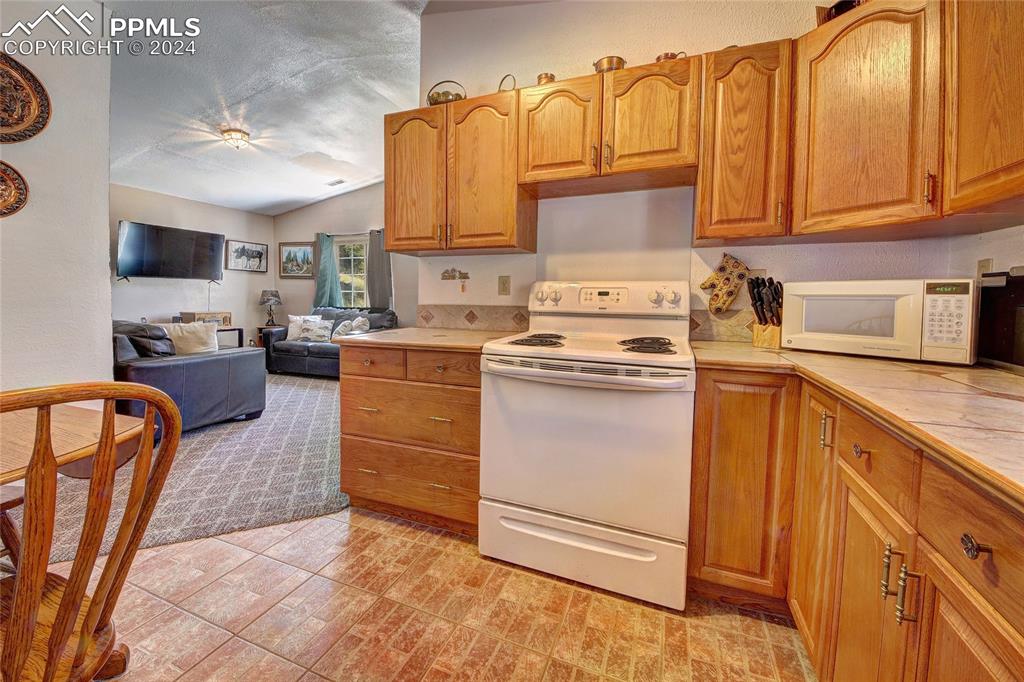68 Valley Road Divide, CO 80814 - Photo 21 of 38 Kitchen with white appliances, light colored carpet, and tile countertops