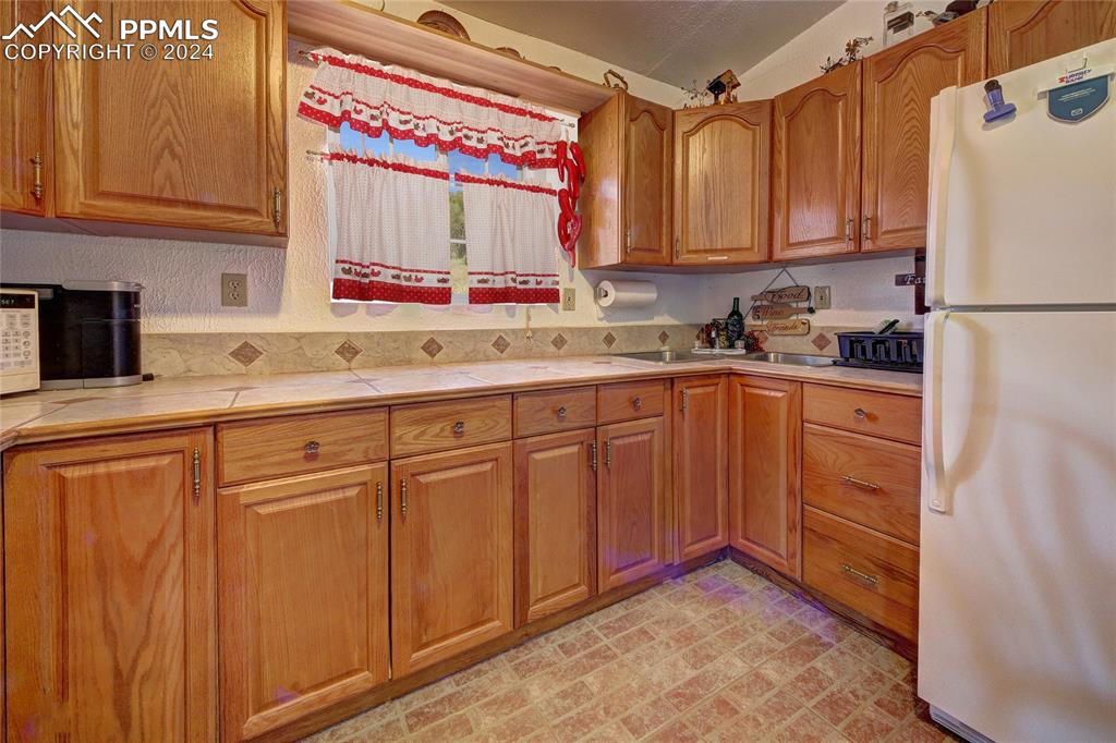68 Valley Road Divide, CO 80814 - Photo 22 of 38 Kitchen with vaulted ceiling, sink, white fridge, and tile counters