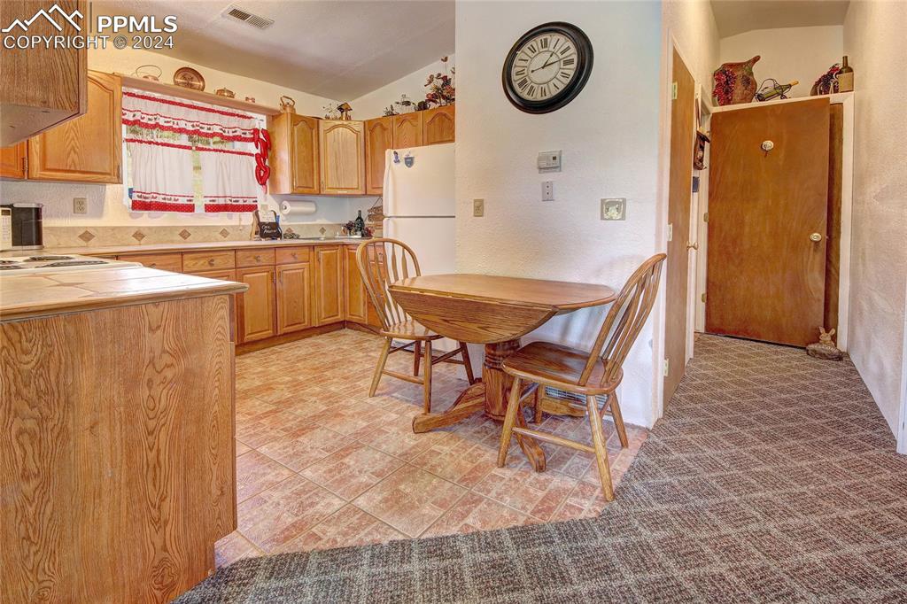 68 Valley Road Divide, CO 80814 - Photo 23 of 38 Kitchen featuring white fridge, vaulted ceiling, tile countertops, premium range hood, and light colored carpet
