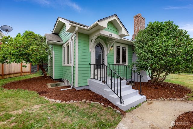 a view of a house with a small yard plants and large tree