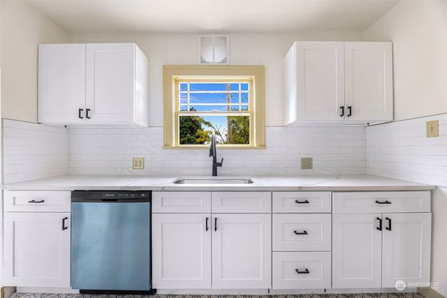 a kitchen with white cabinets and sink